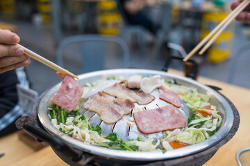 Enjoy the Thai Barbecue called Moo Kata, using chopsticks picking up a piece of sliced pork on the pan and put some vegetables into soup. Thai BBQ Mookata.