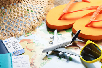 Time for summer vacation. Passports, flight tickets, toy plane and beach accessories on world map,...