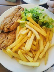 A hearty plate of crispy fried fish, golden french fries, and a fresh green salad, perfect for a satisfying meal