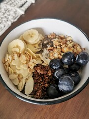 A vibrant and healthy breakfast bowl featuring creamy yogurt topped with blueberries, banana, granola, nuts, and chia seeds.