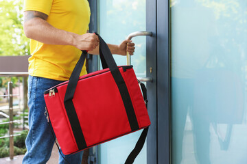 Courier with thermo bag near door outdoors, closeup. Food delivery service