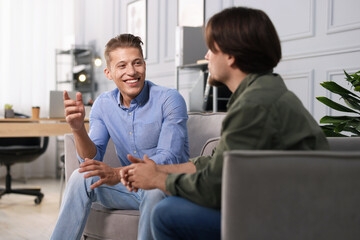 Colleagues having conversation during break in armchairs at office