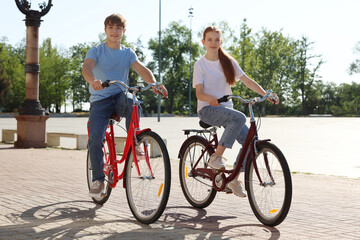 Obraz premium Teenage girl and boy riding bicycles on city street