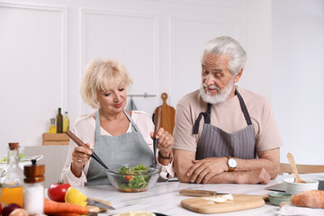 Elderly couple cooking together at marble table in kitchen