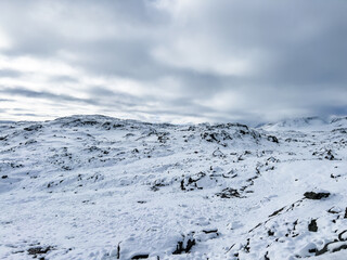 A winter landscape along the Sognefjellsvegen road in Norway, featuring snow-covered mountains and a vast, serene terrain.