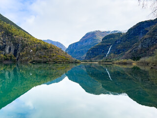 Fototapeta premium Autumn landscape in Skjolden, South Norway, with a calm lake reflecting the mountains and colorful foliage.