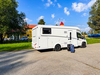 Camper van parked near a hotel with luggage, all set for an exciting road trip