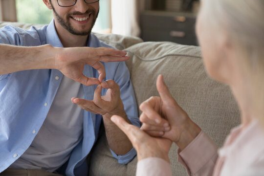 Intergenerational communication using sign language. Close up young man aged woman hold nonverbal conversation with hand gestures. Inclusive dialogue support for person with hearing disability concept