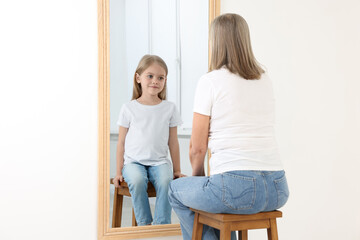 Senior woman seeing herself as child in mirror. Conceptual collage about past and future, flow of...