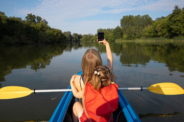 Mother and daughter paddling a canoe on a river surrounded by green trees