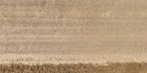 top view of gravel road surface with tractor tire tracks in countryside