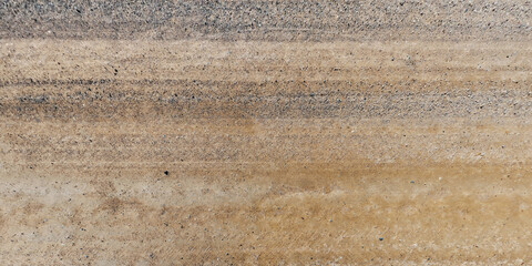 top view of gravel road surface with tractor tire tracks in countryside