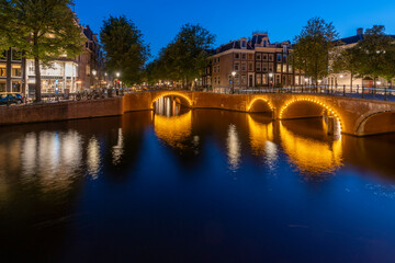 Amsterdam by night in the Netherlands, with canals, lights, reflections int the water