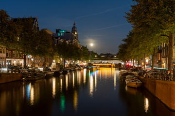 Fototapeta premium Amsterdam by night in the Netherlands, with canals, lights, reflections int the water