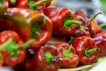Fresh red bell peppers with stems displayed in bulk at a local market, highlighting vibrant color, crisp texture, and natural ripeness.