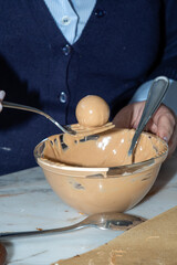 Confectioner placing a truffle in chocolate coating with melted caramel.