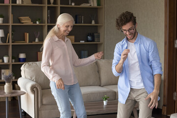 Casual weekend fun. Overjoyed laughing active elderly mom pensioner having fun dancing in modern...