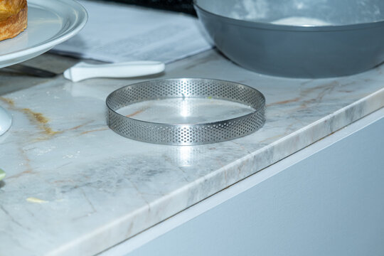 Perforated ring for baking pies on the marble countertop.