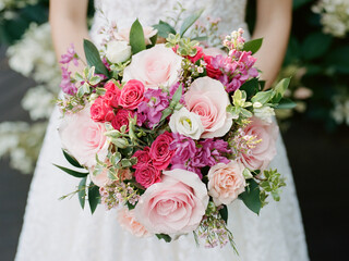 Beautiful bridal bouquet featuring pink and purple flowers held by a bride in a wedding dress