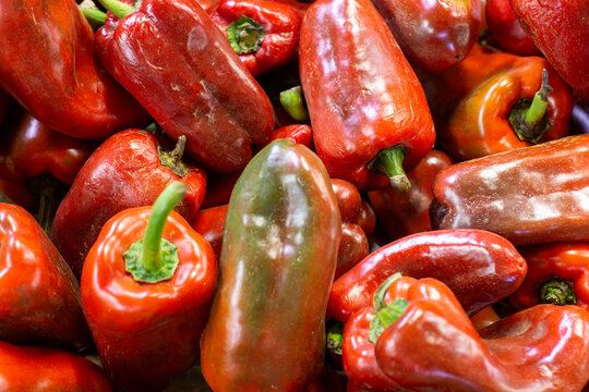 Pile of ripe red peppers showing glossy skins and natural imperfections.