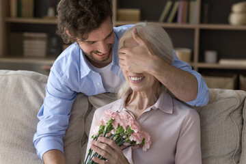 With all my love. Portrait of excited touched senior grandmother sitting on sofa with closed eyes...