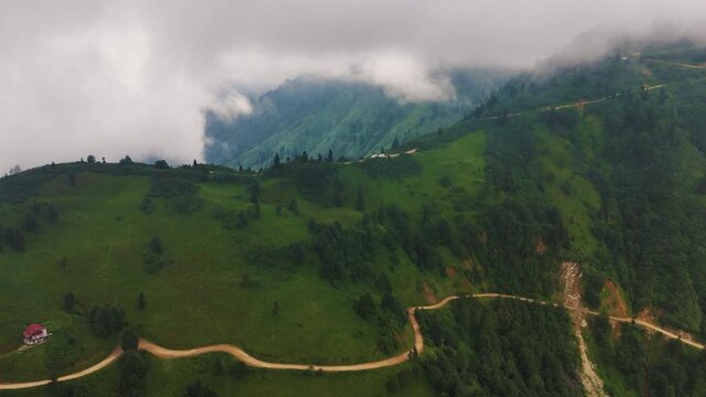 Breathtaking aerial view of a winding dirt road amidst lush green valleys and rolling hills in the Black Sea region of Turkiye