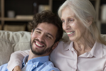 Lifelong connection. Close up portrait caring older age single mum sitting on sofa embracing...