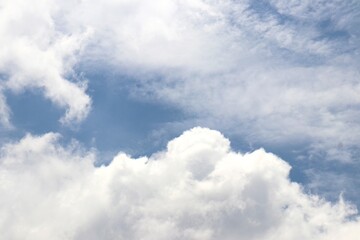 Fototapeta premium Bright blue sky with soft, fluffy white clouds drifting peacefully, creating a serene and refreshing view of nature’s beauty. Suitable for nature and simple background.