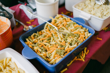 Colorful pasta salad in a blue dish served on a table during a casual gathering