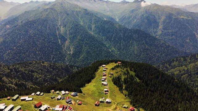 Pokut Plateau showcasing colorful houses nestled amidst lush greenery with the majestic Kackar Mountains in the background