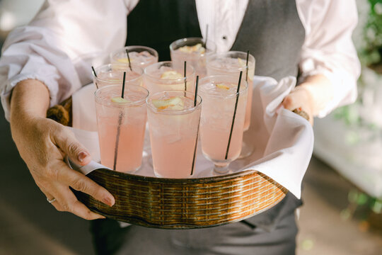 Waiter serves refreshing pink lemonade drinks at a summer event in a bright venue