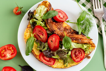 Low-calorie omelette with greens served isolated on green