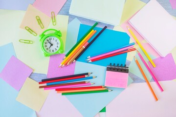 Back to school concept. Alarm clock, stationery and pastel colored paper on table, top view, flat...