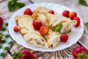 Plate with pancakes and fresh strawberries on a wooden table