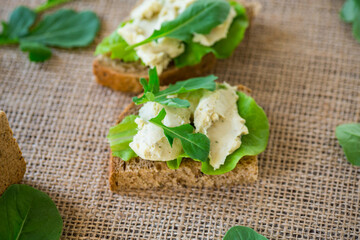 Close-up of a sandwich with herring and lettuce leaves on a burlap tablecloth