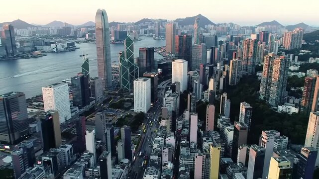 A breathtaking elevated perspective of a modern coastal city's dense financial district, with countless illuminated towers reflecting in the water at twilight.