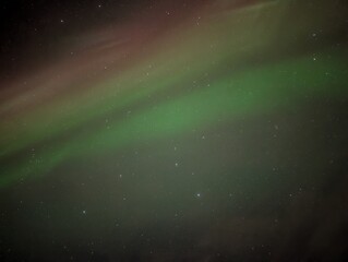 Spectacular green and reddish Northern Lights dance across a starry night sky over Þjótandi,...