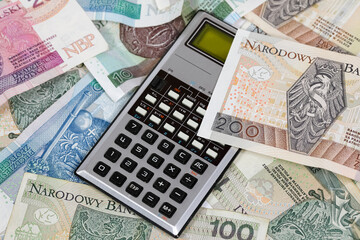 A scientific calculator and Polish zloty banknotes are shown