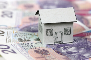 A tiny paper house and banknotes of the Polish zloty