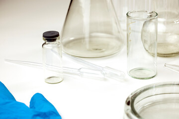Laboratory equipment including glass beakers, pipettes, and a vial on a white surface. 