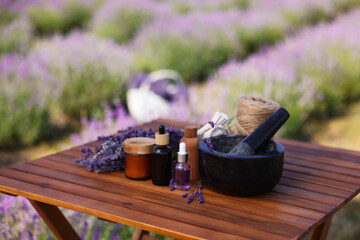 Making natural cosmetics. Beautiful lavender flowers and other ingredients on wooden table in field