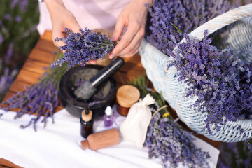 Making natural cosmetics. Woman with lavender flowers and other ingredients at wooden table in...