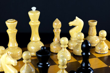 A close-up view of a chessboard with yellow and black chess pieces. The pieces include pawns,...