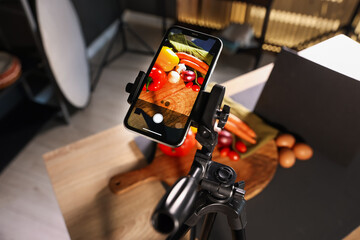 Shooting vegetables with smartphone in studio, focus on screen. Professional food photography