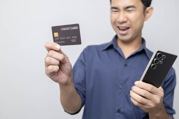 A man stands holding a cell phone, laptop, and credit cards. He is smiling happily and making various gestures for the camera.

