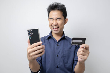 A man stands holding a cell phone, laptop, and credit cards. He is smiling happily and making various gestures for the camera.

