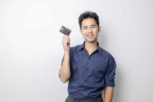 A man stands holding a cell phone, laptop, and credit cards. He is smiling happily and making various gestures for the camera.

