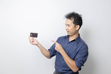 A man stands holding a cell phone, laptop, and credit cards. He is smiling happily and making...