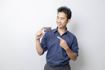 A man stands holding a cell phone, laptop, and credit cards. He is smiling happily and making...