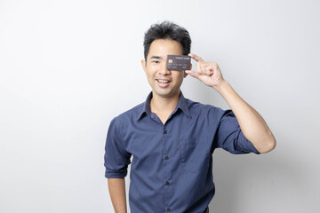 A man stands holding a cell phone, laptop, and credit cards. He is smiling happily and making...